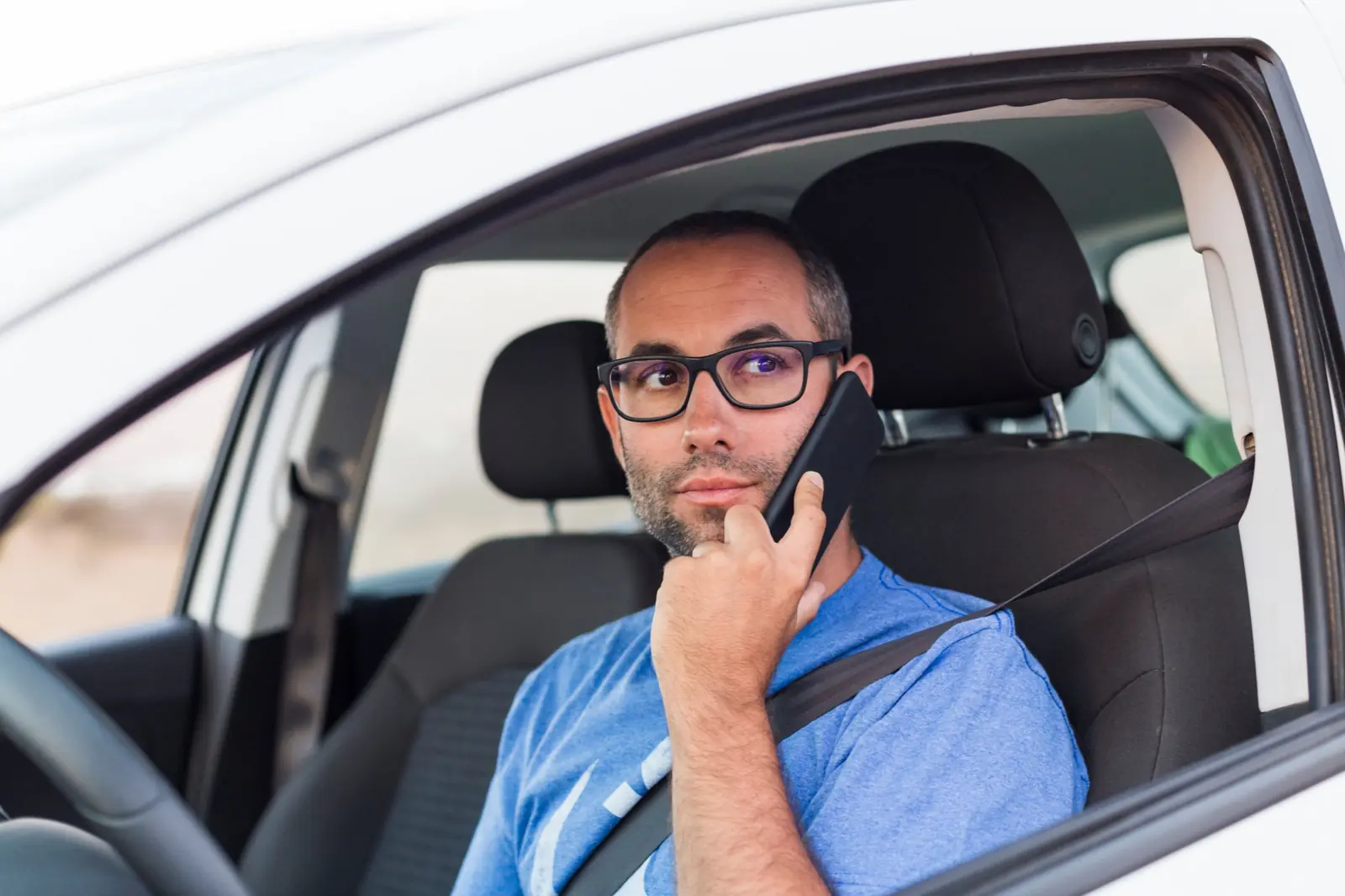 An on-call nurse taking a call in his car